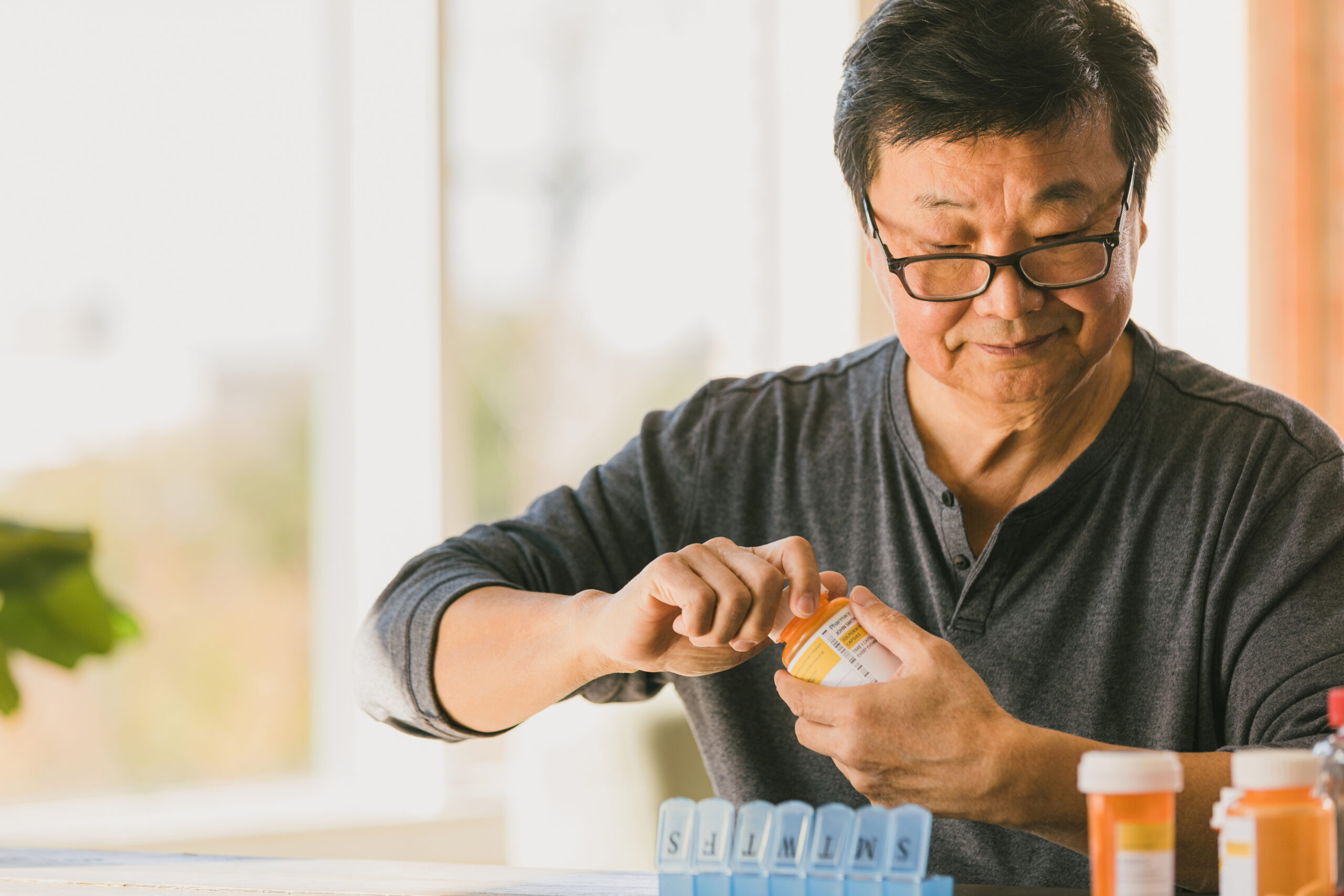 Retired man sorts medication into pill organizer