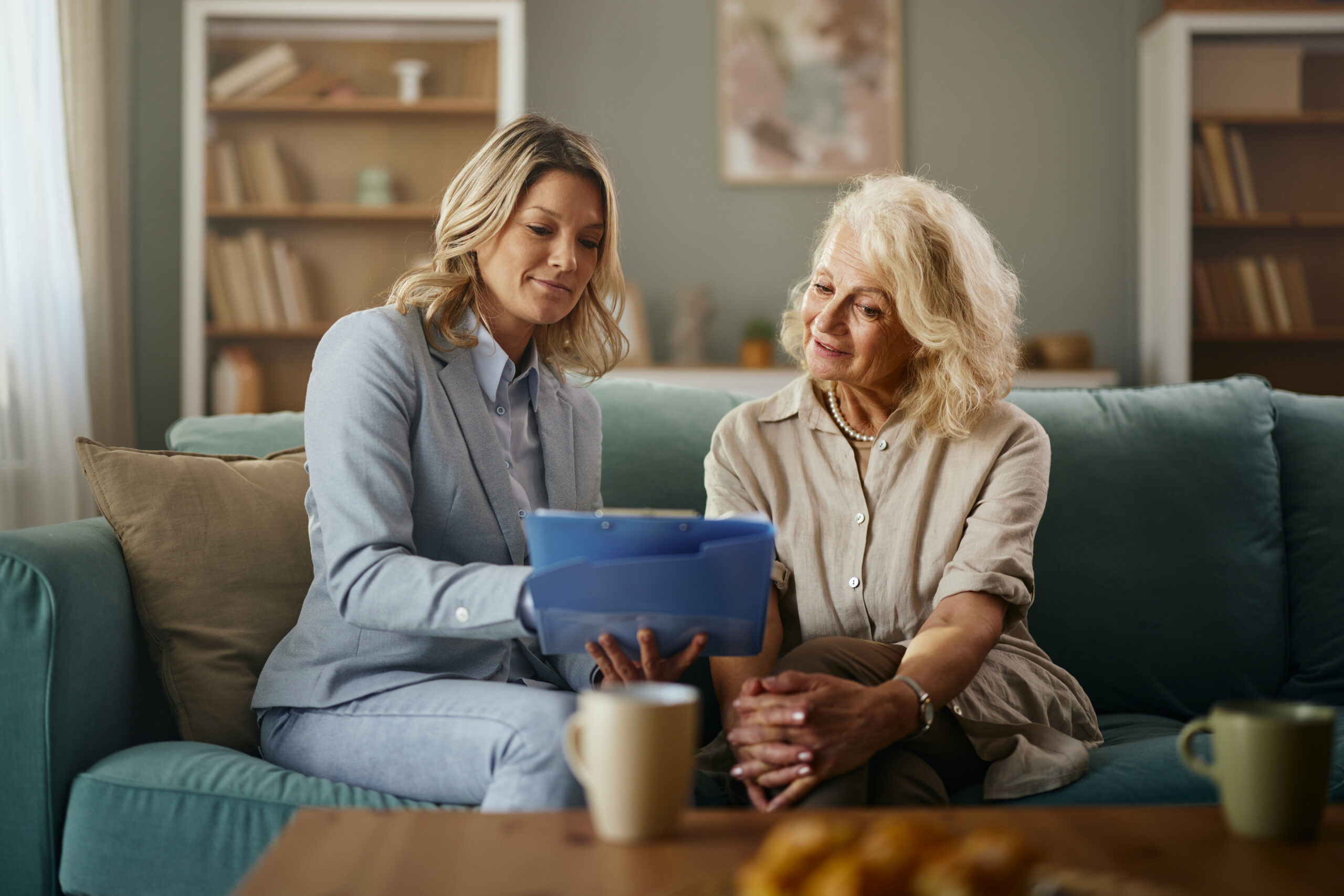 Smiling female Champion Rep and senior woman analyzing health plan options during a meeting in the living room.